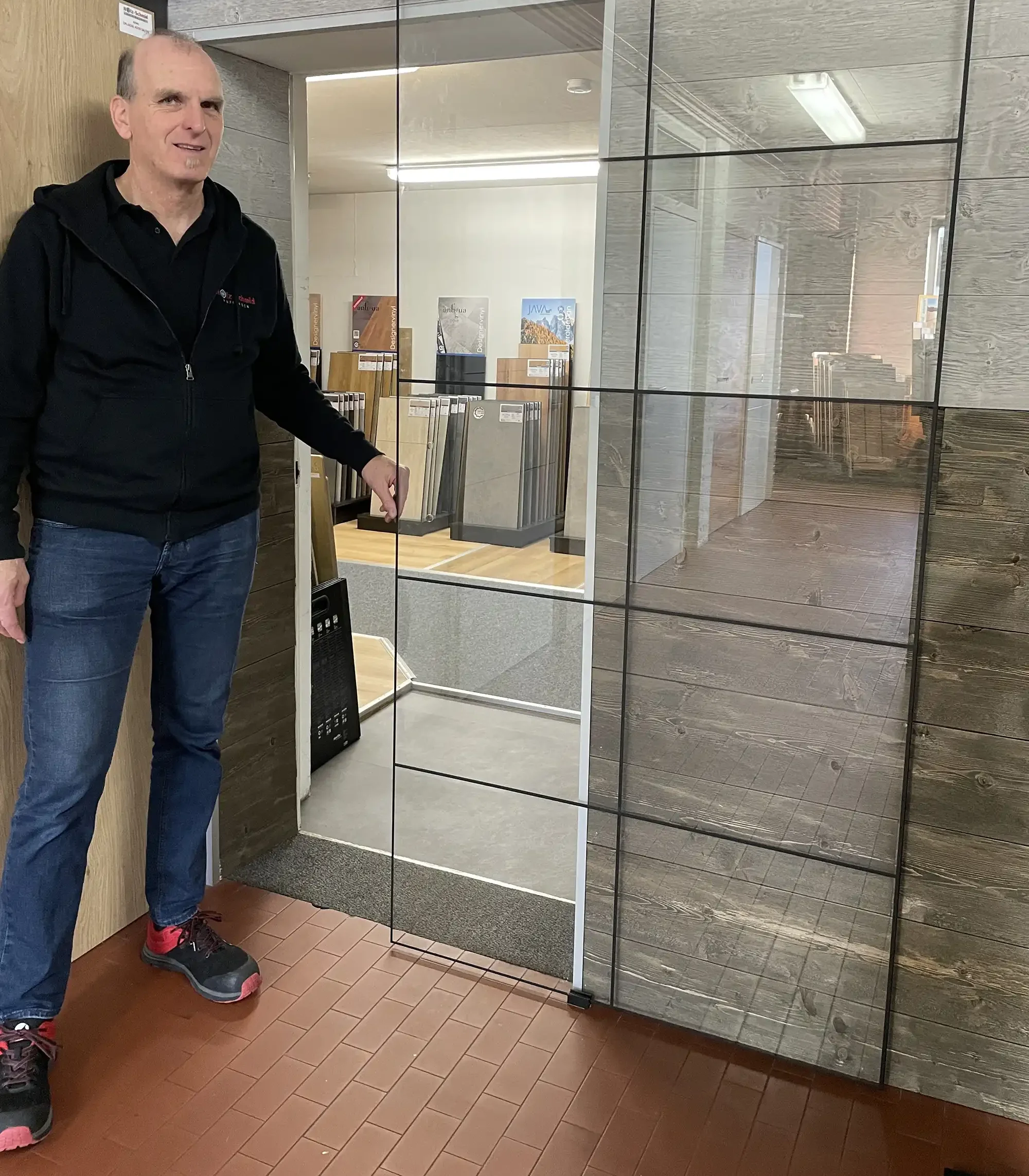 Herr Schmid öffnet eine Glasschiebetür im Loftdesign in seiner ausstellung