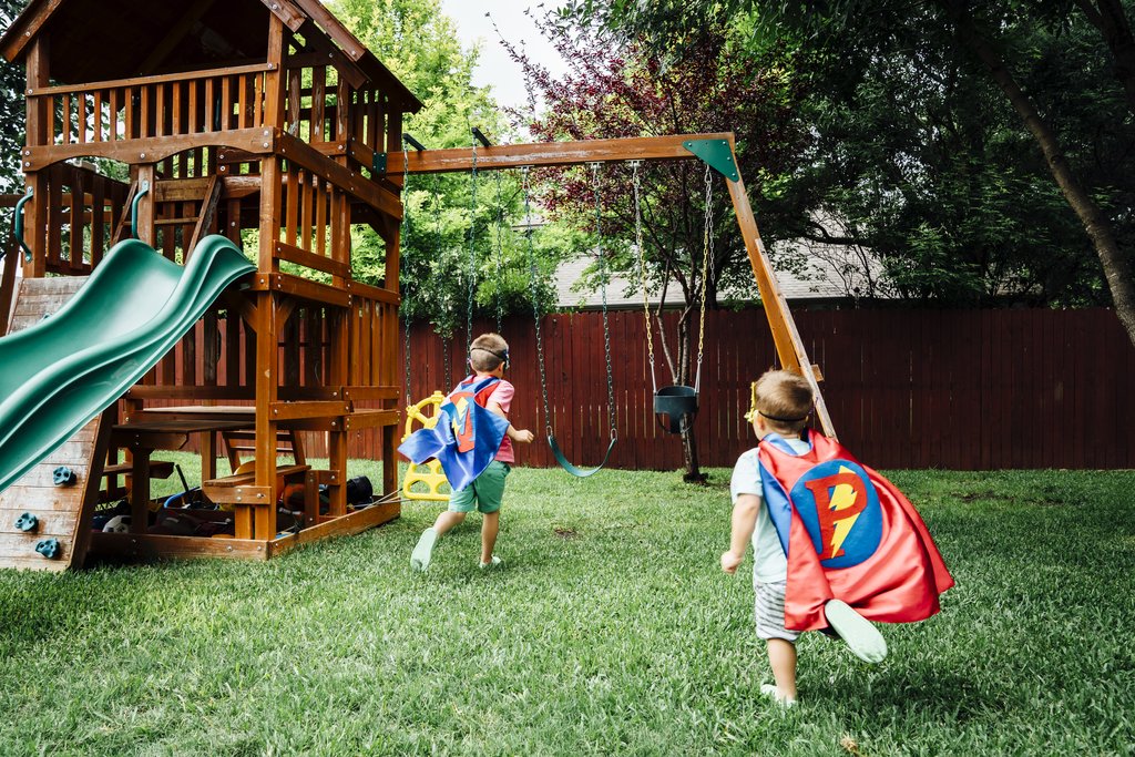 Ein Spielturm mit Schaukel und 2 Kindern 